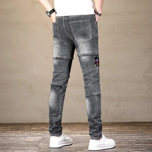 Détail des empiècements déchirés et de l'étiquette colorée sur ce jean slim pour homme