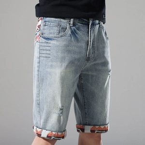 Detailed shot of light blue denim shorts with ethnic style embroidery and distressed patterns