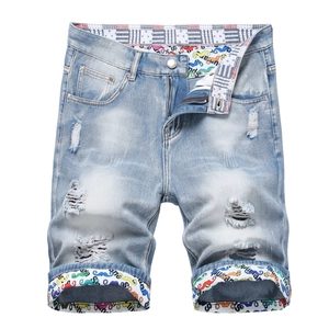 Men's light blue distressed denim shorts with graffiti print details on white background