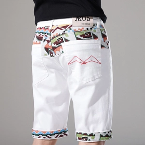 Dettaglio di pantaloncini di jeans bianchi da uomo con patchwork etnico e ricamo rosso dietro