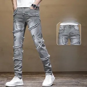 Detail of light grey slim fit biker jeans with distressed stitching and knee rips