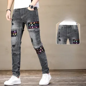 Détails du jean gris slim fit avec des déchirures et des écussons imprimés colorés
