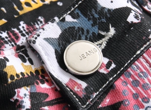 Detailed macro view of a silver jeans button on printed stretch denim fabric for men