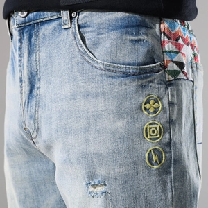 Detail of light blue denim shorts with colorful ethnic fabric side trim and embroidery