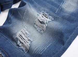 Detailed macro view of distressed blue denim shorts showing ripped holes and fabric textures