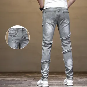 Detail view of grey slim fit biker jeans showing distressed whiskers and ripped knee effects