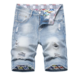 Close-up of ripped denim shorts with star pattern lining and graffiti cuff details