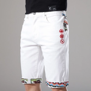 Dettaglio degli shorts in denim bianco con nastro etnico e icone ricamate rosse