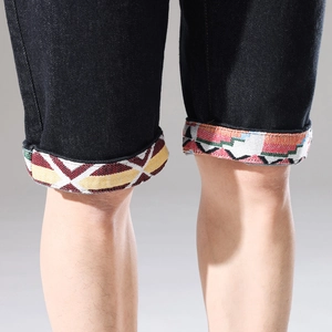 Detaillierte Nahaufnahme bunter ethnischer Stickerei am Saum schwarzer Denim-Shorts