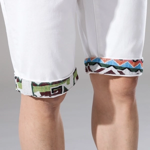 Dettaglio dei pantaloncini di jeans bianchi con ricamo etnico geometrico sull'orlo