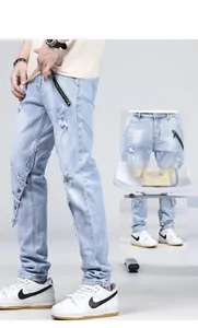 Détail du jean bleu clair montrant la sangle boutonnée à la cheville et le tissu délavé