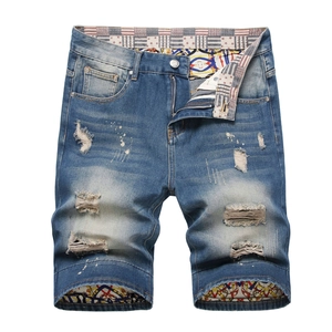 Detailed view of men's blue distressed denim shorts with American flag lining accents