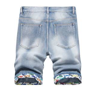 Detail of light blue denim shorts featuring rolled cuffs with unique colorful cartoon print