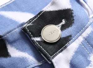 Gros plan d'un bouton métallique argenté sur un jean extensible imprimé taches d'encre