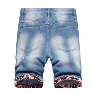 Detail of light blue distressed denim shorts with paint splatters and star pattern cuffs
