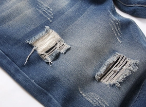 Dettaglio macro di pantaloncini di jeans strappati con trama denim blu lavato vintage