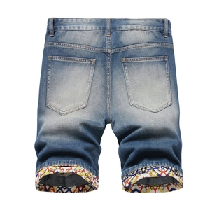 Detail view of denim shorts featuring wash effects and a unique geometric printed lining cuff