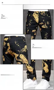 Detail view of men's slim fit black jeans with gold abstract print and metal buckle