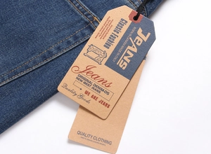 Dettaglio dell'etichetta in carta vintage e cuciture arancioni su pantaloncini di jeans