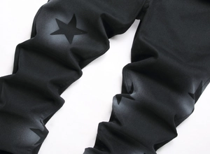 Detailed view of black denim pants featuring gray gradient star prints and fabric texture