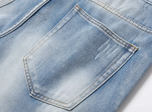 Detailed close-up of the back pocket with topstitching on men's washed blue denim shorts