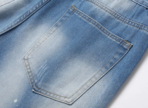 Detailed close-up of blue denim back pocket with orange stitching and white paint splatter
