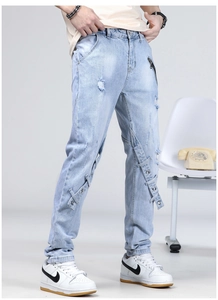 Détails du jean bleu clair avec patchs usés et sangles décoratives à boucles métal