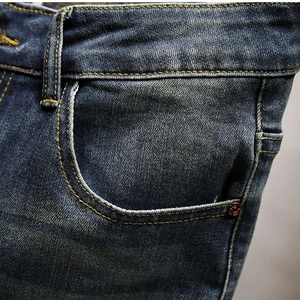 Macro shot of blue denim shorts showing yellow stitching and copper rivet details