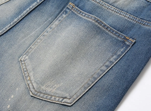 Close-up of washed blue denim shorts showing orange stitching and distressed pocket detail