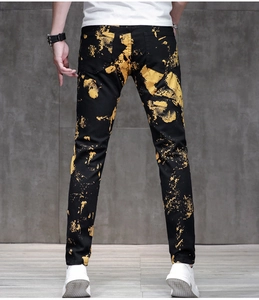 Detail view of mens slim fit black jeans with bold gold paint splash print from the back