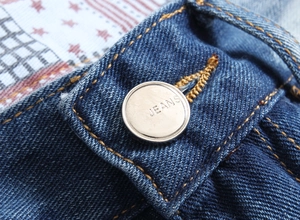 Detail of dark blue denim waist with yellow stitching and a silver metal jeans button
