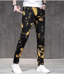 Detail of slim-fit black men's jeans featuring bold yellow graffiti paint splatter print