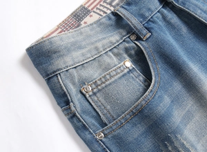 Détail macro du short en jean bleu montrant les rivets et la doublure imprimé drapeau