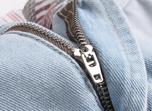 Macro detail of high-quality metal zipper and reinforced stitching on blue denim shorts