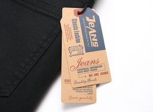 Close-up of vintage kraft paper tags on black denim jeans with thick twill texture