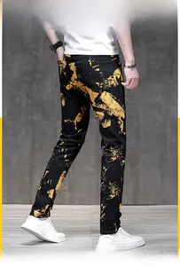 Close-up of men's slim fit black jeans featuring vibrant yellow paint splatter print pattern