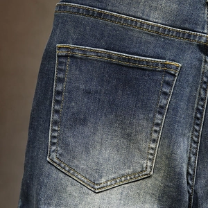 Macro shot of dark blue denim shorts featuring orange contrast stitching and washed fabric