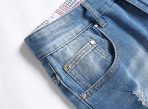 Detailed macro view of light blue denim shorts with contrast stitching and metal rivets