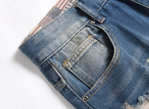 Detailed close-up of distressed denim jeans waist with striped lining and metal rivets