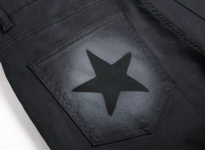 Detail of black denim back pocket featuring a hand-painted star with spray-painted vintage effect