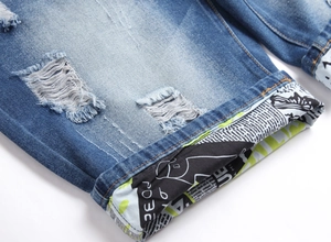 Close-up of distressed denim shorts showing ripped texture and printed cuff detail