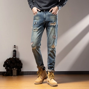 Macro view of distressed details and ripped knee on light blue straight-leg denim jeans