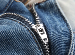 Gros plan sur la fermeture éclair en métal et coutures jaunes du short en jean