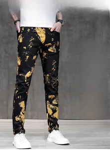 Detailed close-up of slim fit black trousers featuring bold yellow splash print patterns