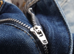 Vista dettagliata della cerniera in metallo e delle cuciture gialle sui pantaloncini denim
