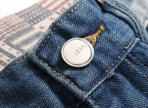 Detail of waist area showing metal JEANS button and orange stitching on blue denim shorts