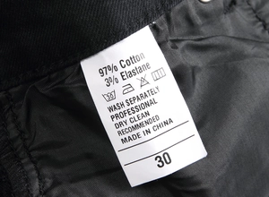 Detail view of the fabric care label showing material composition on black denim jeans