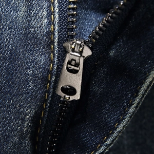 Detail macro shot of high-quality metal zipper and ginger stitching on denim shorts