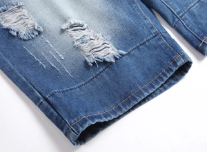Macro view of distressed denim texture with ripped holes and orange stitching details