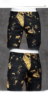 Close-up of men's black slim jeans featuring artistic yellow paint splash and KB logo print
